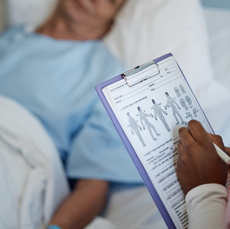 Medical Professional Reviewing Patient's Health Chart Medical professional checking patient's health chart while patient rests in hospital bed under care showing detailed examination and attentive care