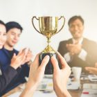 Businessman show thumbs up with trophy, reward, winner, champion and successful for business